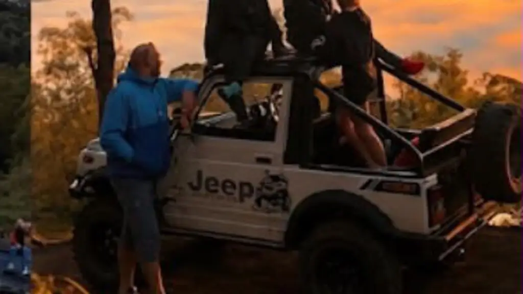 A group of travellers standing on and beside a white open-top jeep in golden morning light above a sea of cloud
