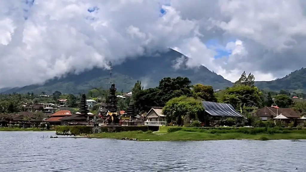 The tiered shrines of Ulun Danu Bratan on the shore of a rippling lake, under a mountain half hidden in white cloud